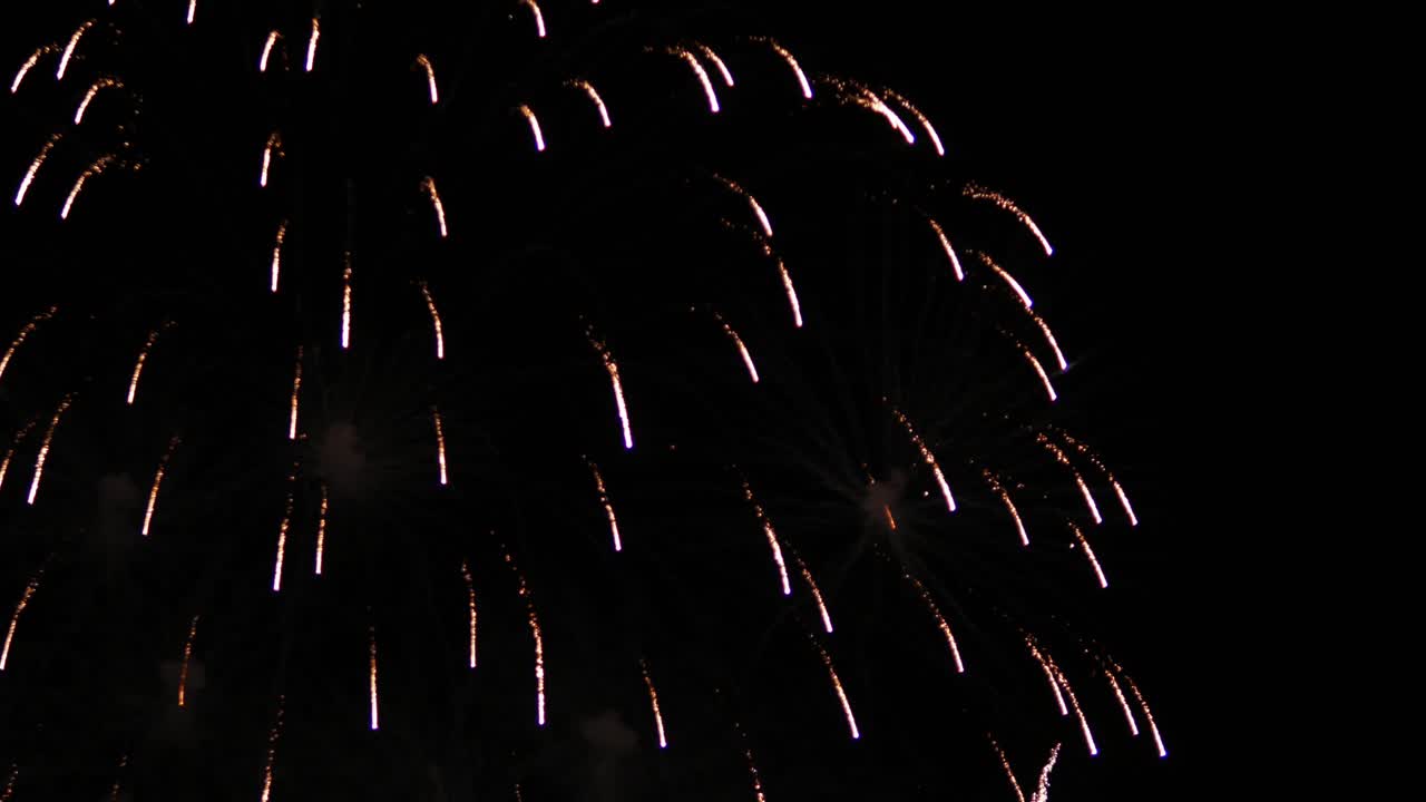 explosión sincronizada de luces brillantes y coloridas, cayendo de nuevo al suelo y iluminando el cielo nocturno