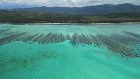 aerial dolly in above crystal waters towards buildings of domaine de deva, new caledonia