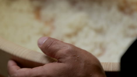 Sushi-Man---Mixing-Japanese-White-Rice-Moistened-With-Vinegar-Mixture-Into-The-Wooden-Basin---high-angle-shot