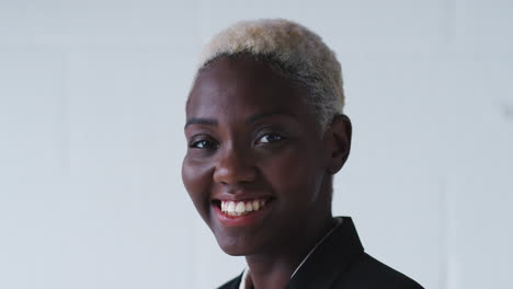 Portrait-Of-Smiling-Young-Businesswoman-Wearing-Suit-Standing-Against-White-Studio-Wall