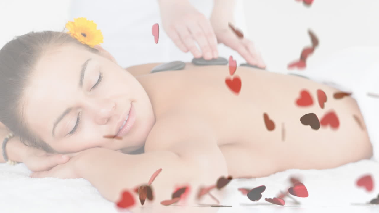 뜨거운 돌 마사지를 받으며, 떠다니는 심장 모양의 애니메이션으로 휴식을 취하는 여성