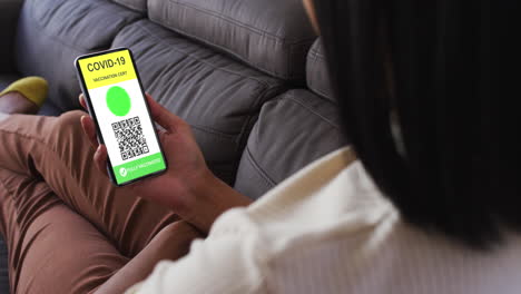 mujer en casa con un teléfono inteligente con certificado de vacunación contra la covid y código qr en la pantalla