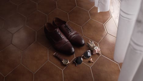 brown leather shoes with groom accessories on tiled floor