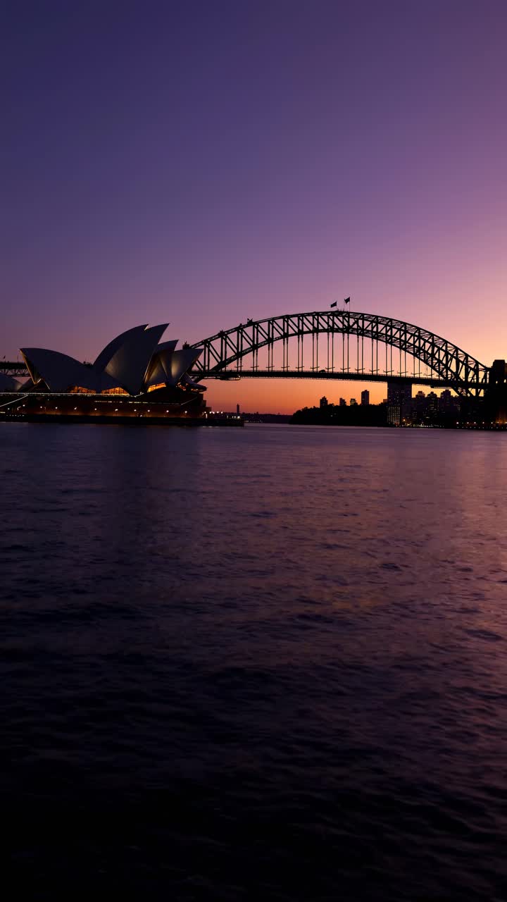 A stunning video still of Sydney's skyline at dusk, featuring the Opera House and Harbour Bridge