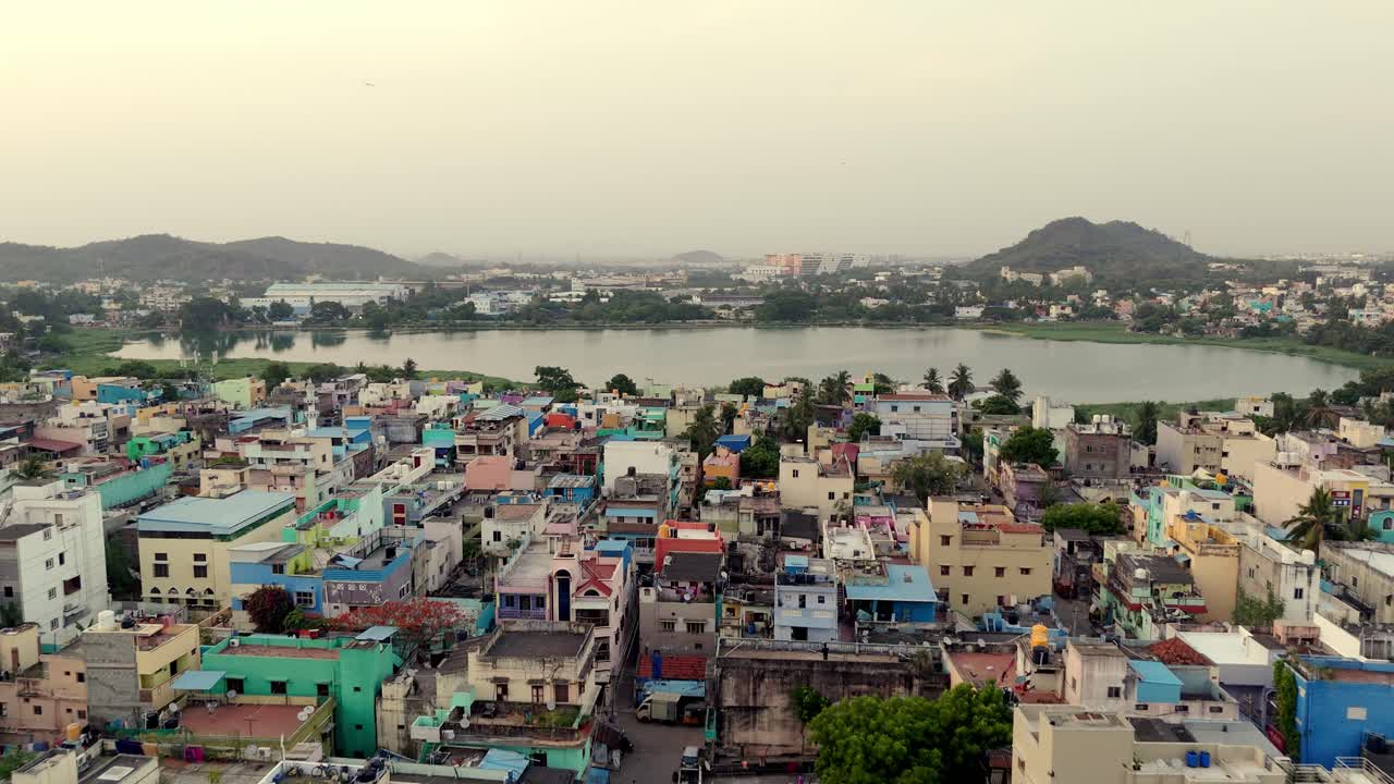 Aerial shot of pond in between a city with hills at background on a misty day.