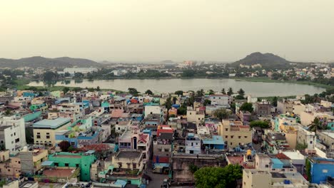 aerial shot of pond in between a city with hills at background on a misty day.