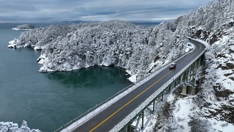 無人機拍攝追蹤一輛車在冬天穿過欺騙橋,到處都是雪