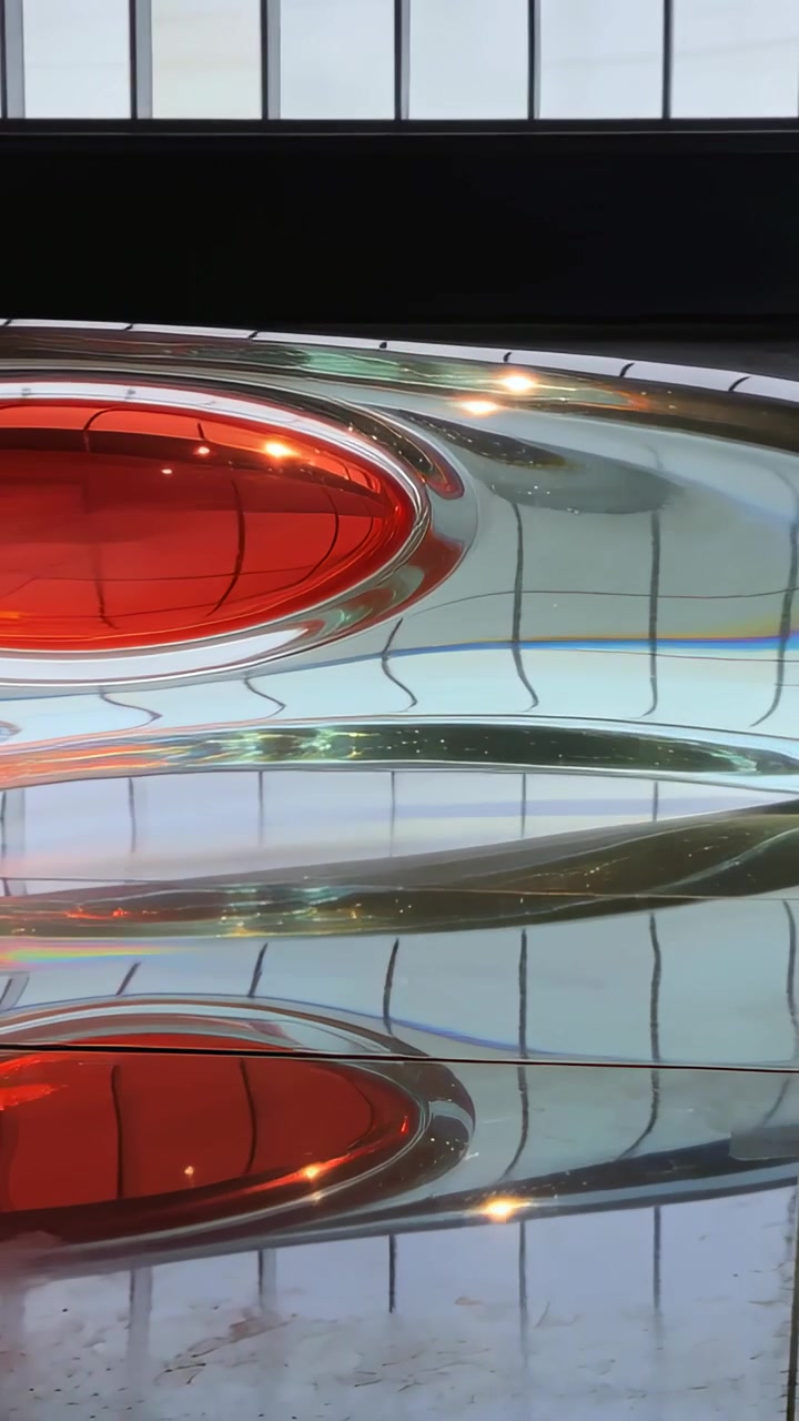 Video verticale: Panoramica della telecamera che rivela una scultura trasparente in una galleria, con luce che sposta lenti ovali rosse