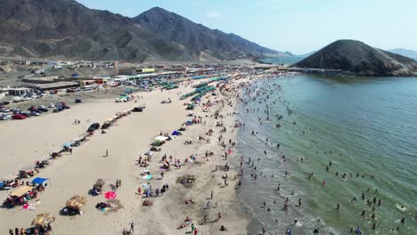 aerial drone captures huge crowd of people enjoying scenic beach on madeira island, with vibrant coastline and mountains creating stunning backdrop to lively beach scene in portugal