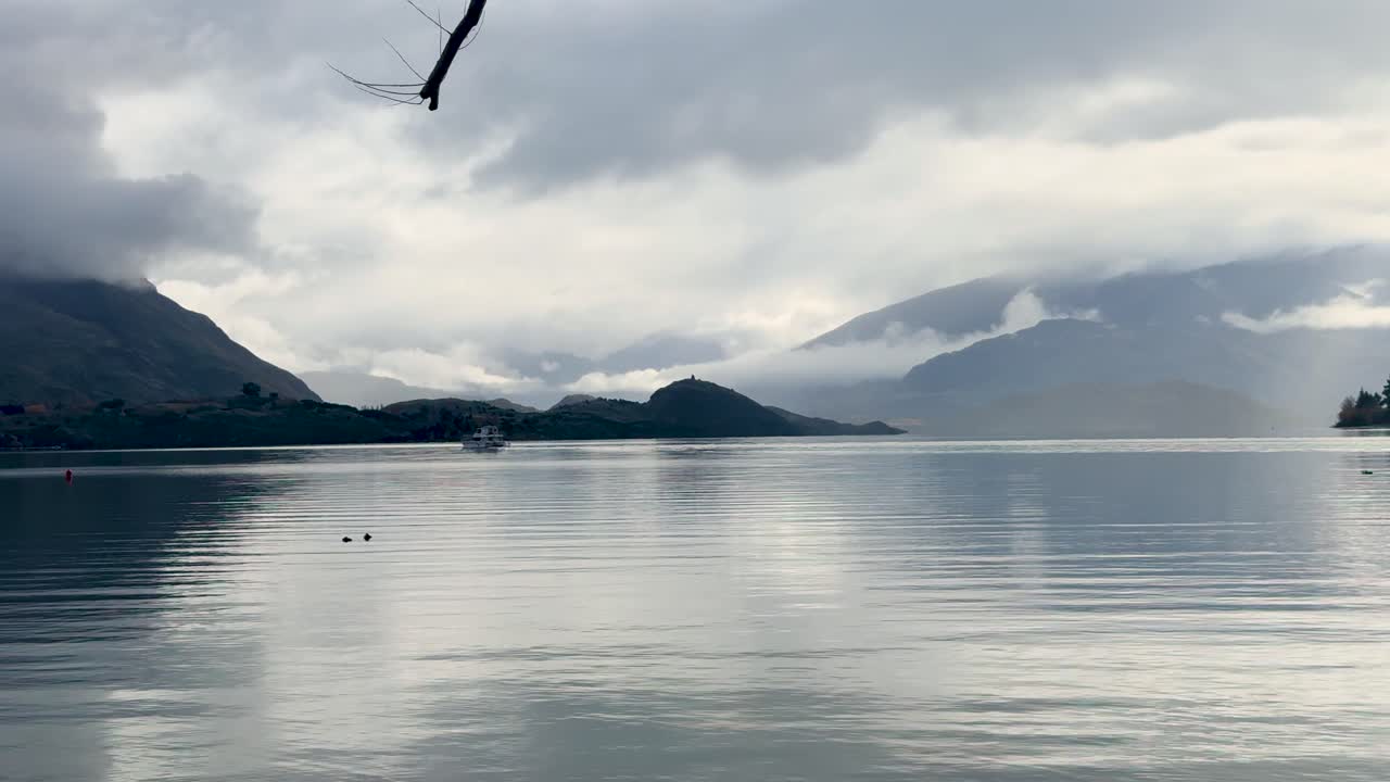 A serene view of Lake Wanaka with mountains and clouds, captured in soft, diffused lighting