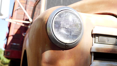 dramatic push in shot of the front of an old rusty vintage truck fender in middl america with glass headlight and grill in the sunlight