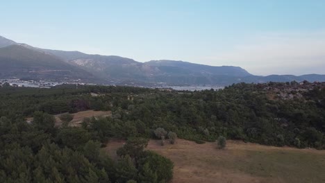 retreating drone shot of above the woodlands of sillyon, revealing the town below and showing the mountains from afar, situated in antalya province in turkey