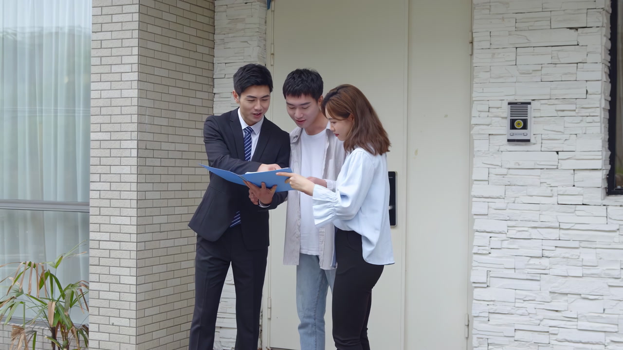 Welcoming new homeowner, salesperson real estate realtor introduces clients couple to new living space holding a clipboard with essential documents, discussing contract terms