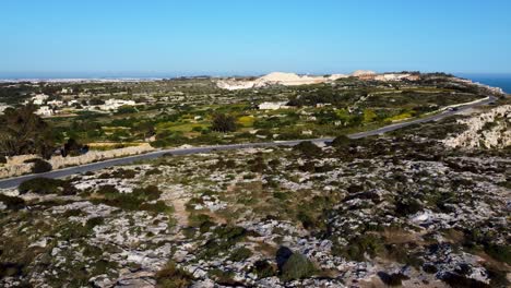 Aerial-drone-view,-flying-forward-towards-Malta-town-on-the-coast,-Old-buildings-visible-in-distance