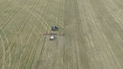 New-agricultural-crop-being-seeded-on-vast-open-field,-tilt-up-aerial-view