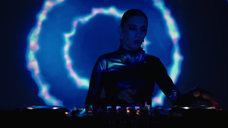 a female dj mixing music on turntables in a dark club.