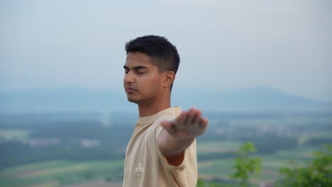 práctica de hatha yoga en la cima de la colina verde con un hombre asiático con los ojos cerrados al amanecer