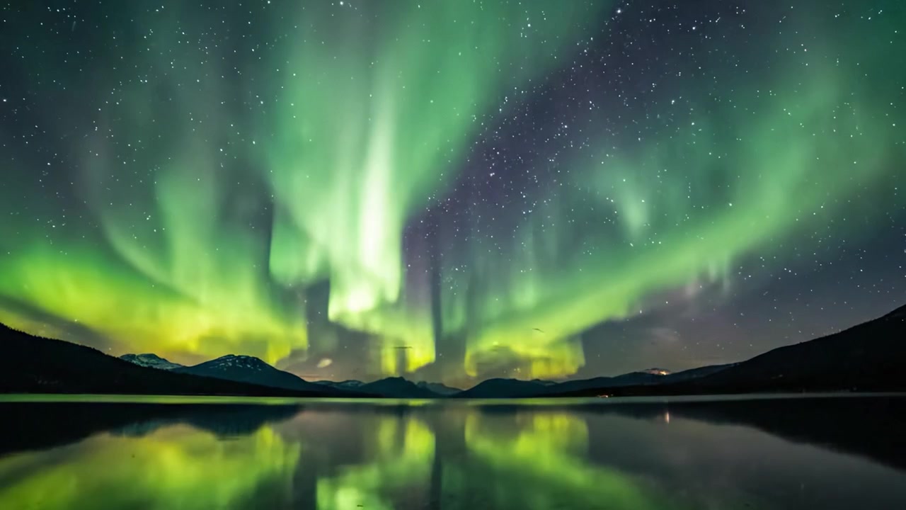 Spettacolare spettacolo dell'aurora boreale che illumina il cielo notturno sopra un lago tranquillo, con un riflesso a specchio dell'aurora boreale e uno sfondo stellato.