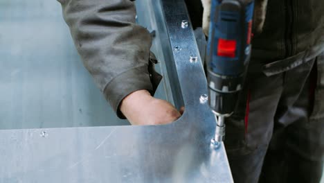 worker using screwdriver with nozzle while tightening bolts on metal block