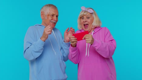 una pareja de mayores mirando el teléfono juntos con entusiasmo.