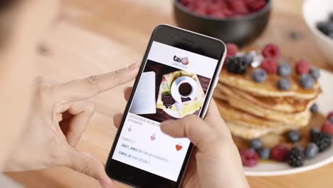 mujer usando un teléfono móvil durante el desayuno en la cocina