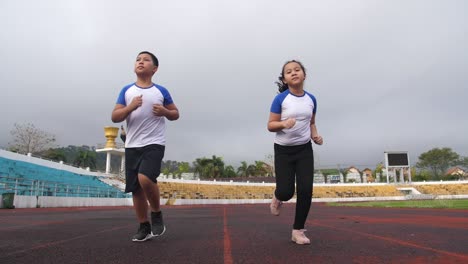 boy and girl running at stadium