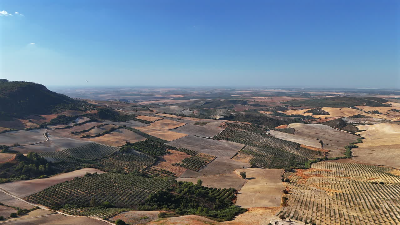 Aerial view showing dry fields and farmlands near Cote Castle in Andalusia, southern Spain, under clear summer sky