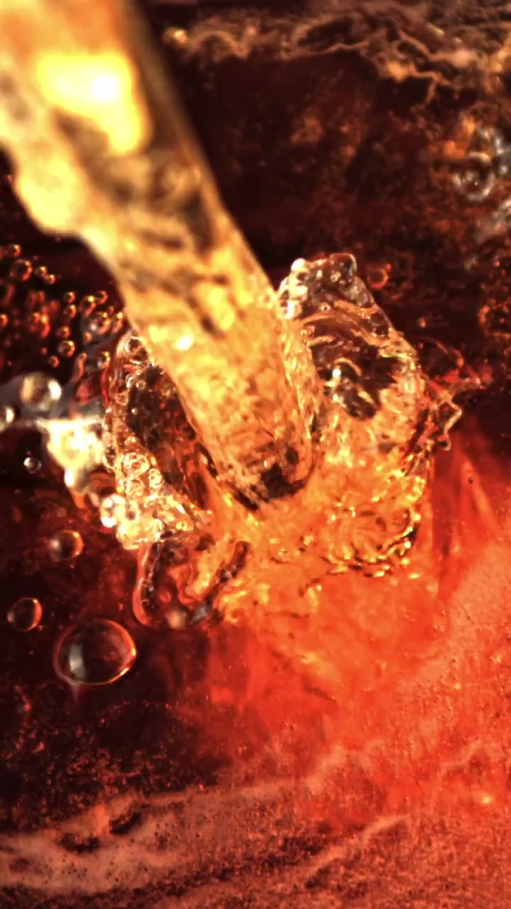 Primo piano macro di liquido ambrato dorato che si versa e schizza