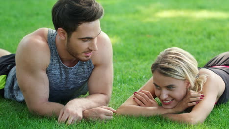 smiling couple talking together and lying on grass in park. happy couple