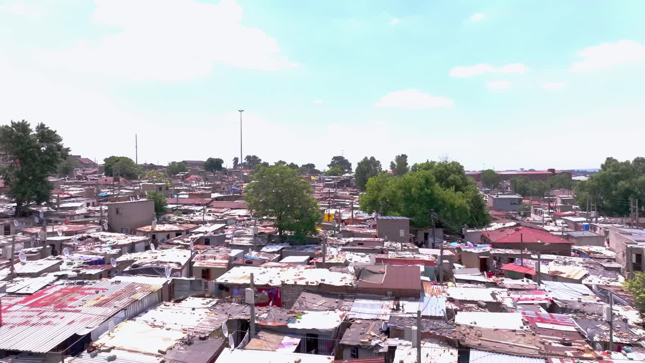 Close-up Aerial orbital panning shot of informal settlement in Alexandra Township, Johannesburg, South Africa, on a sunny day with scattered clouds