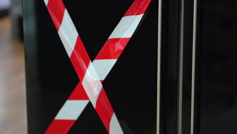 man opening a refrigerator with red and white striped tape on the door