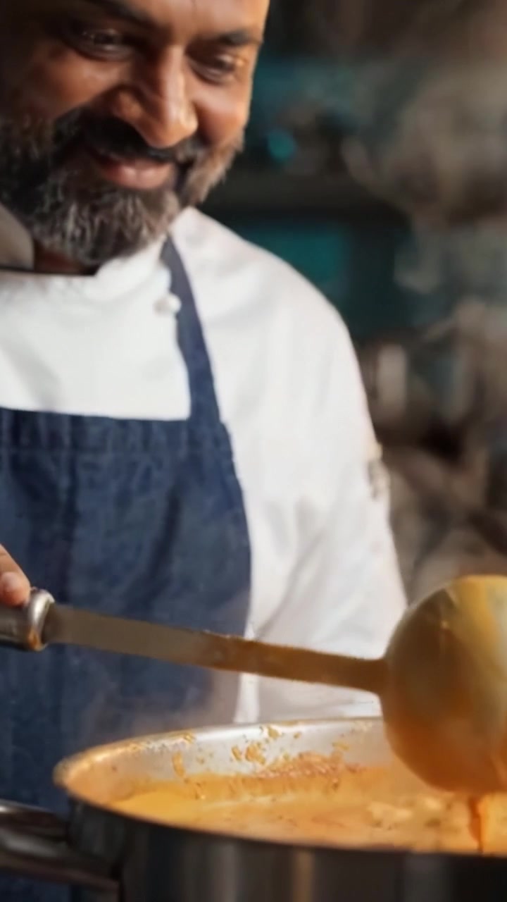 Chef esperto che cucina un piatto delizioso in una pentola fumante, mescolando gli ingredienti con cura e precisione in cucina, creando un pasto saporito da gustare per gli ospiti