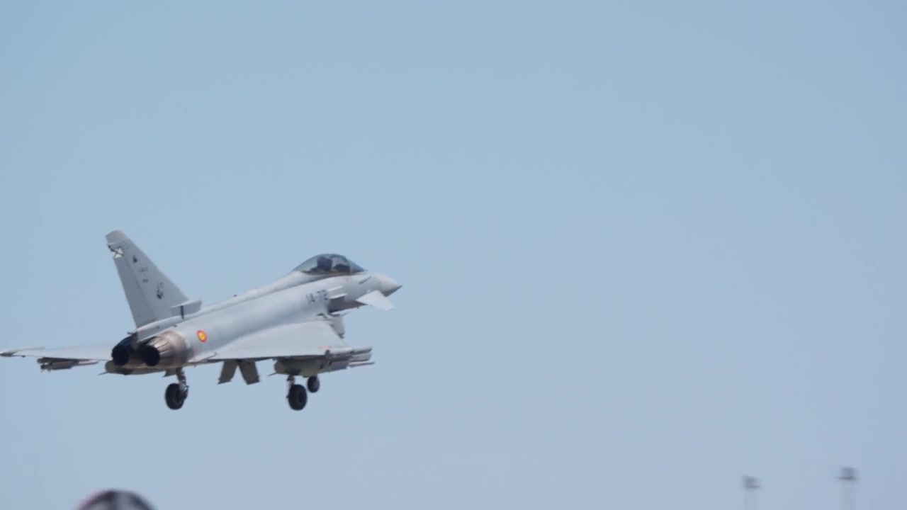 Fighter jet landing with gear down over airbase