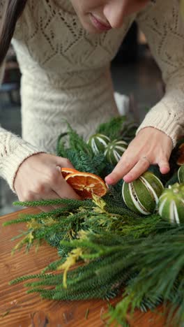 woman making a christmas wreath with dried oranges