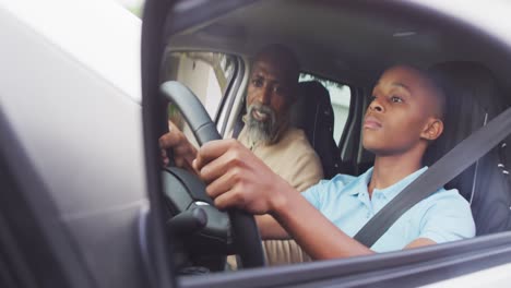 Video-Eines-Fokussierten-Afroamerikanischen-Vaters,-Der-Seinem-Sohn-Das-Autofahren-Beibringt