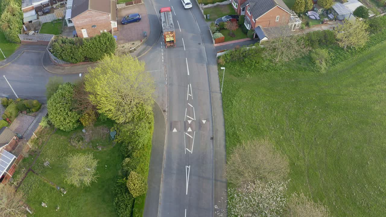 쓰레기통 트럭, 쓰레기 수거 차량은 남자들이 도시의 중산층 지역에 있는 쓰레기 압축기에 재활용 쓰레기통을 싣는 동안 도로 위로 올라갑니다.