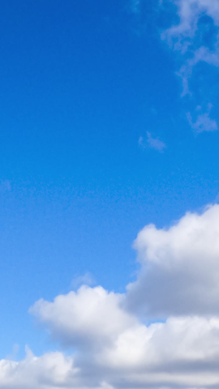 Soft puffy white clouds floating in the azure sky. Clouds quickly transforming in the atmosphere. Low angle view. Timelapse. Vertical video