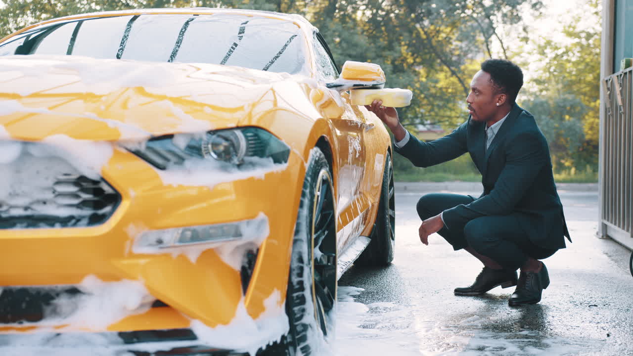 사업복 을 입은 남자 가 노란색 스포츠카 를 고 있다