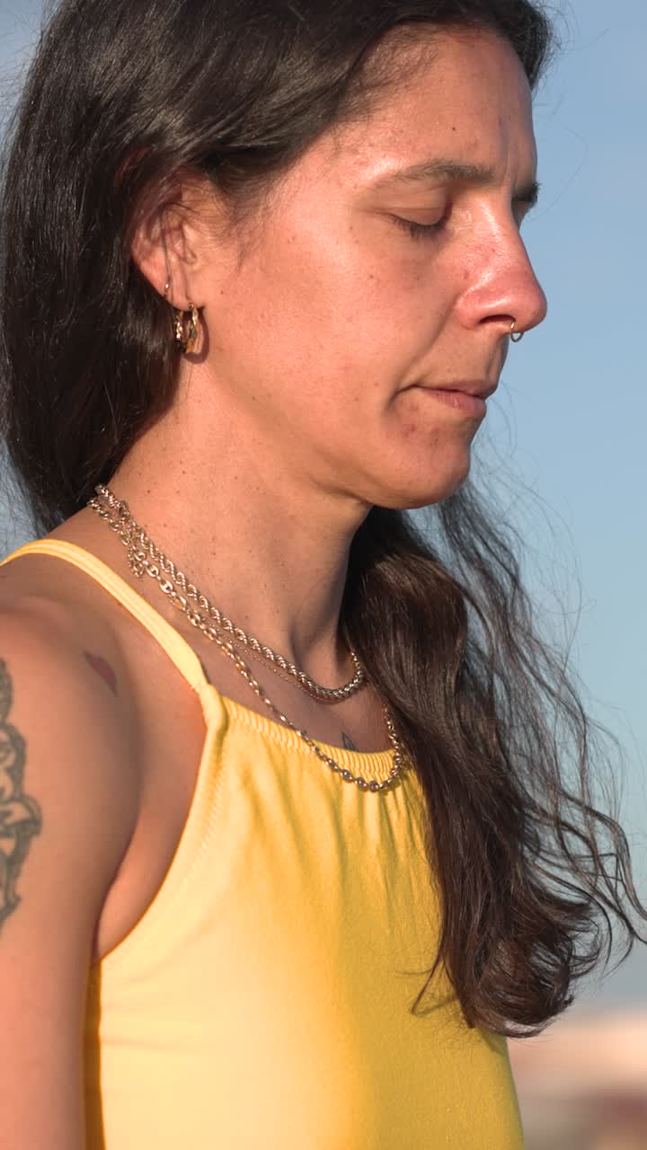 Donna che medita nella posizione yoga Sukhasana sulla spiaggia con gli occhi chiusi