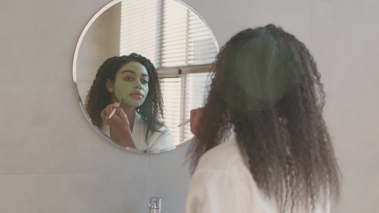 Woman Applying Facial Mask in Bathroom