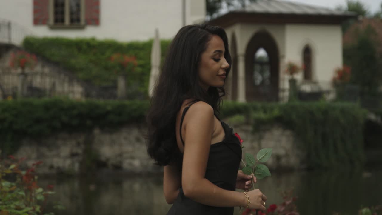 mujer con rosa en la mano camina y mira hacia atrás en cámara lenta