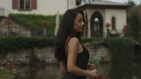 woman with rose in hand walks and looks back in slow motion