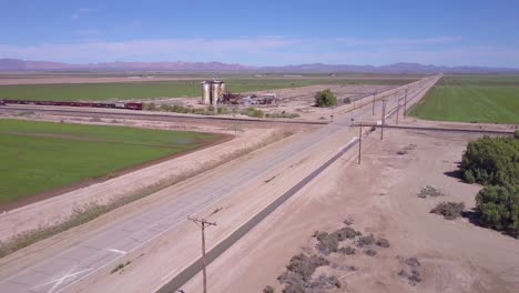 A-high-angle-aerial-over-a-lonely-abandoned-road-through-a-rural-area-past-water-tower-foreground-1