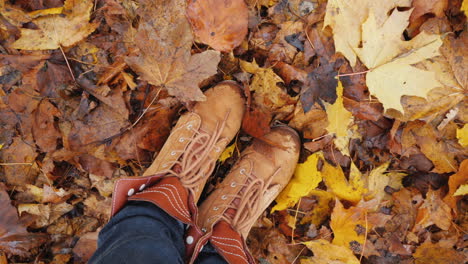 feet in autumn boots on fallen autumn leaves the camera rotates