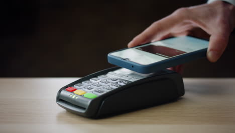 cashless payment using smartphone on modern bank terminal indoors close up.