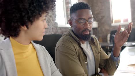 Focused-diverse-colleagues-discussing-work-at-table-in-office-in-slow-motion