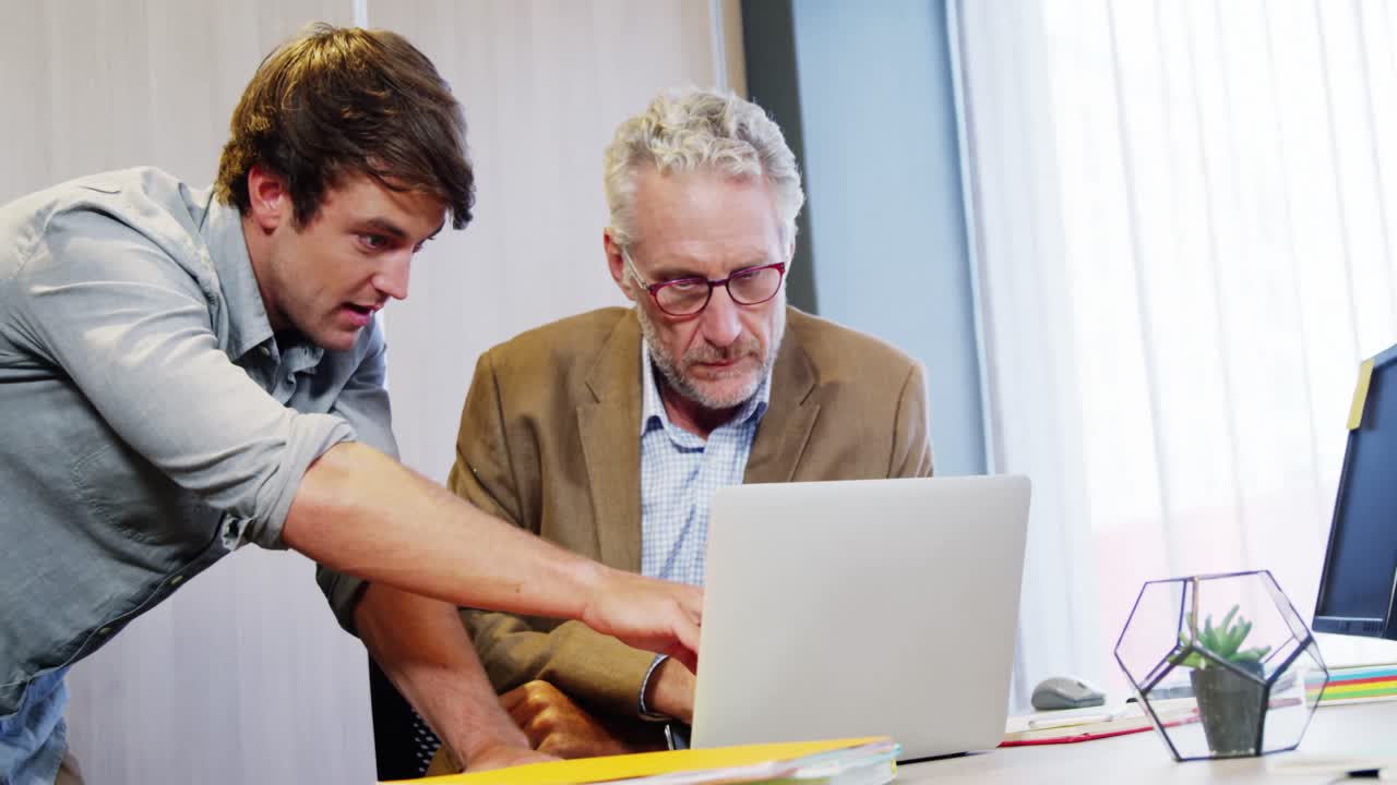 Businessman and coworker discussing over laptop