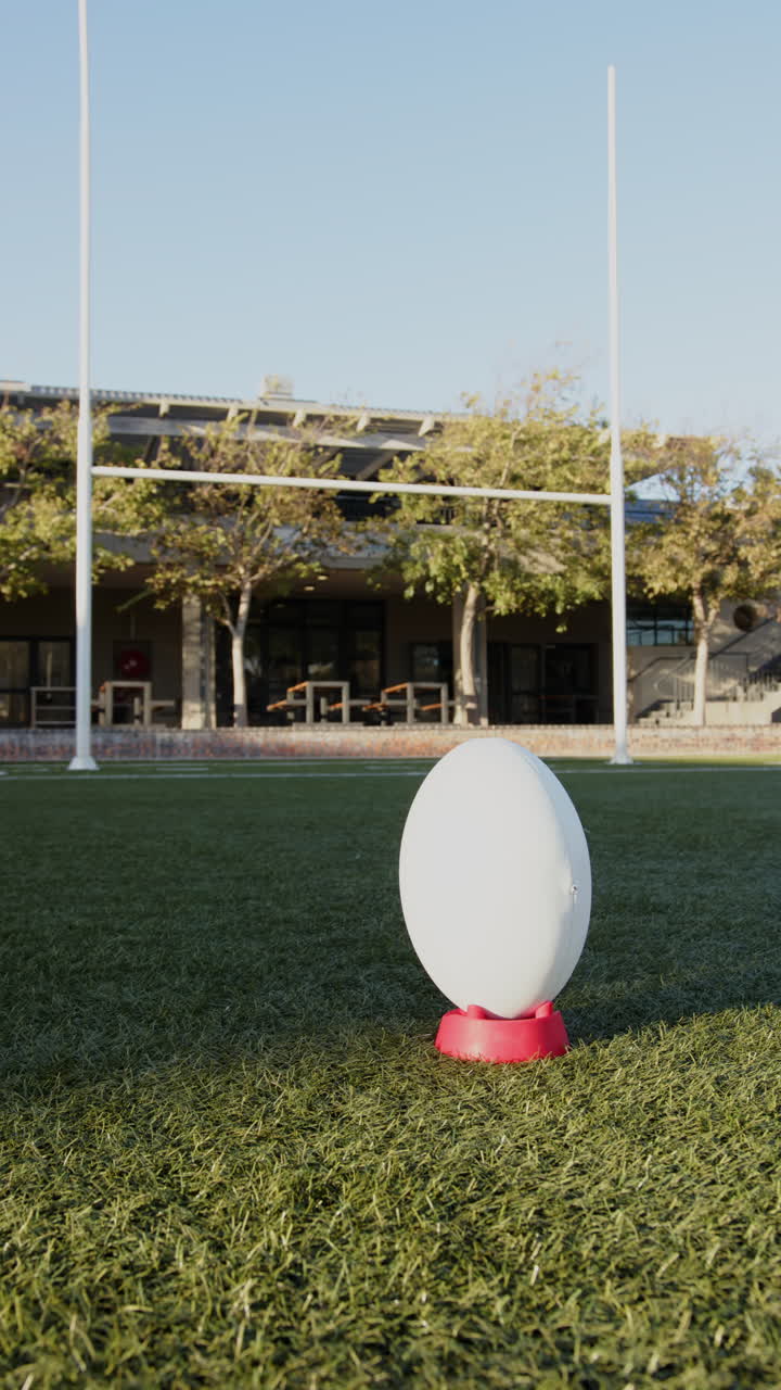 Vertical video: Rugby ball on tee ready for kick on sunny outdoor field