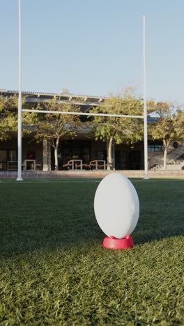 vertical video: rugby ball on tee ready for kick on sunny outdoor field