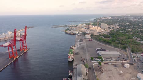 vuelo de regreso al puerto de haina oriental con vista al río haina y al mar caribe en una cálida tarde, donde podemos observar la zona industrial